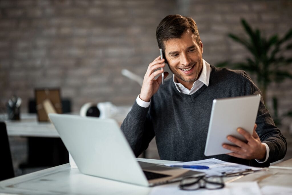 Um empreendedor está mexendo no computador, conversando com um advogado sobre cobrança judicial.