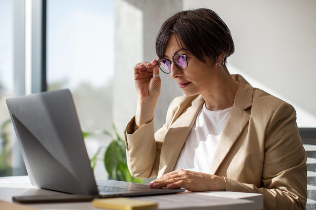 A imagem mostra uma mulher, com seu computador no escritório. Ela está procurando a melhor conta digital para igrejas.