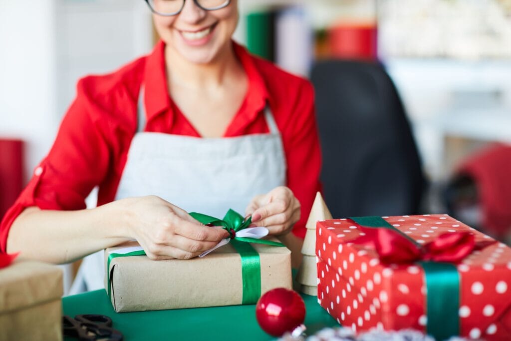 A imagem mostra uma vendedora embalando presentes. Ela está entendendo como vender mais no natal.