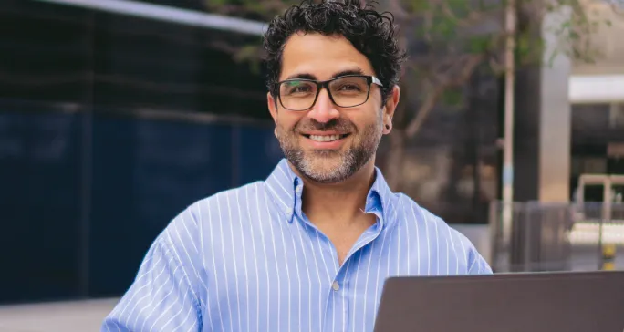 Homem branco usa óculos e sorri após criar sua conta PJ.